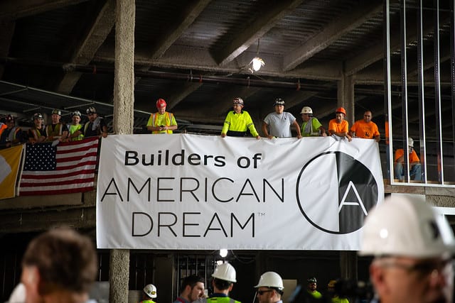 Builders unveil a banner reading "Builders of American Dream"