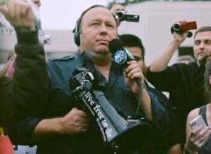 Alex Jones wearing headphones, holding microphone and bullhorn