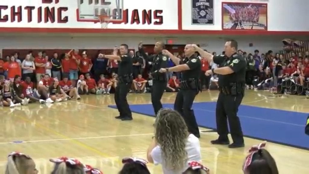 Police officers dance in front of students at high school pep rally. (Courtesy of Major Milo Thornton)