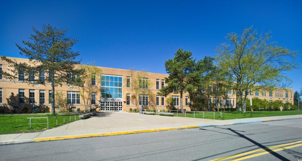exterior shot of beige school building with trees and walkway