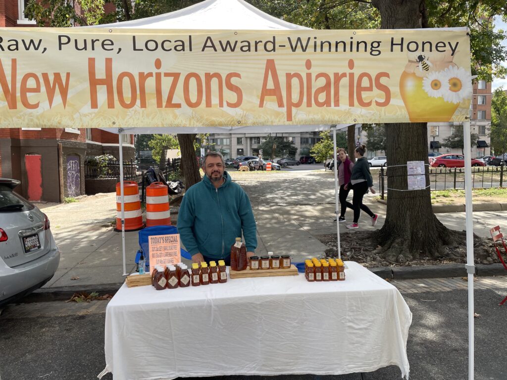 Martin Posse stands behind a table selling honey at a farmers' market in Washington, D.C.