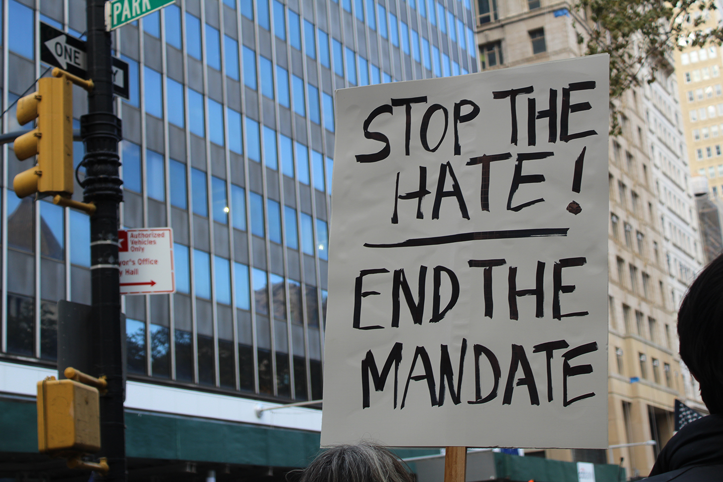 A poster reads "Stop the hate! End the mandate"
