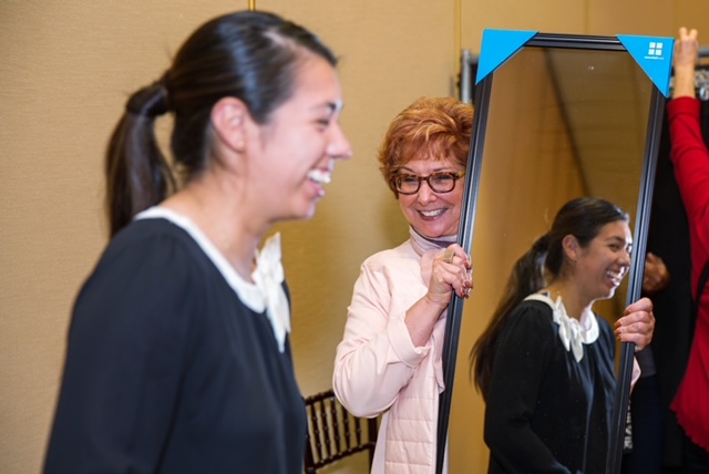 A woman holds a mirror for a client