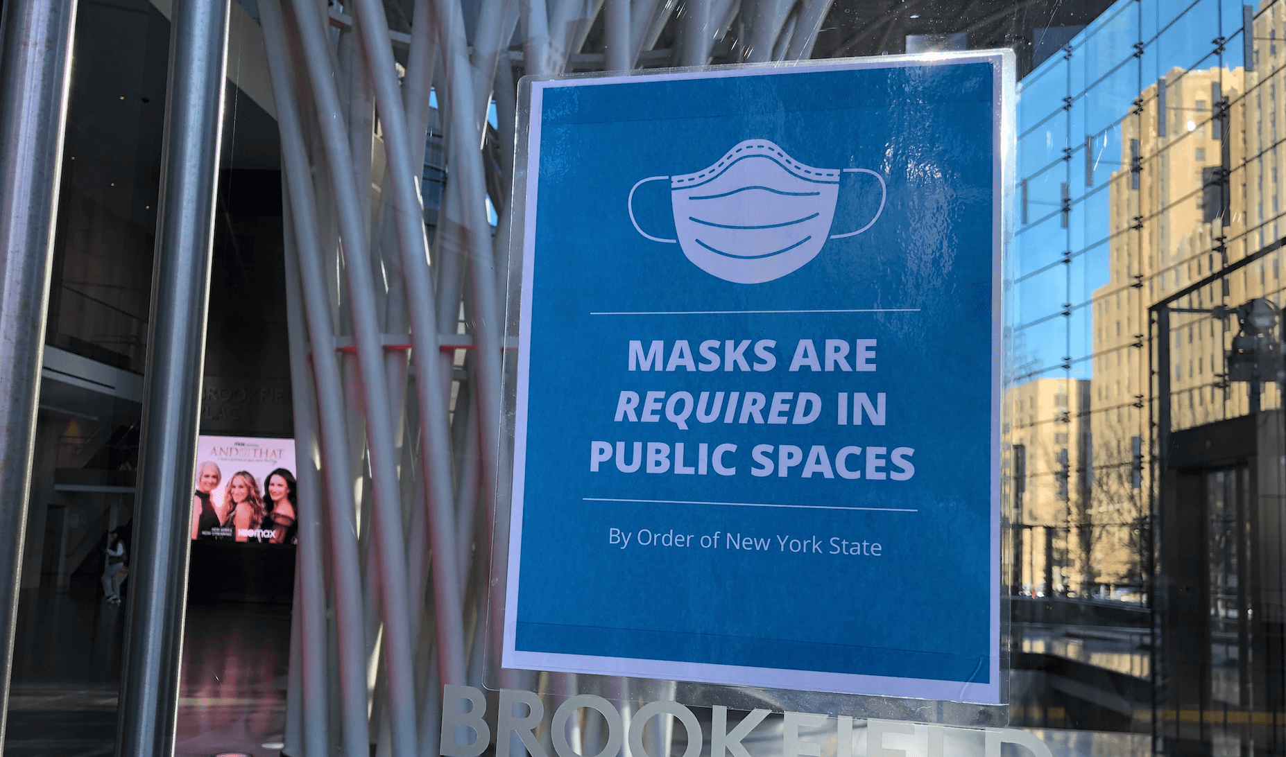blue sign with a picture of a mask and the words, "Masks are required in public spaces"