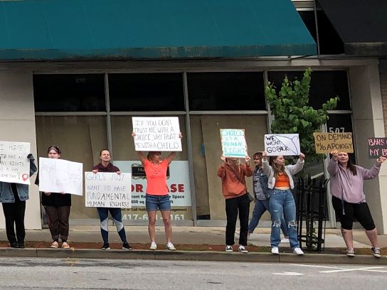 A group of protesters hold up signs