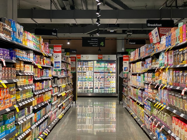 An aisle of a grocery store facing the dairy refrigerators