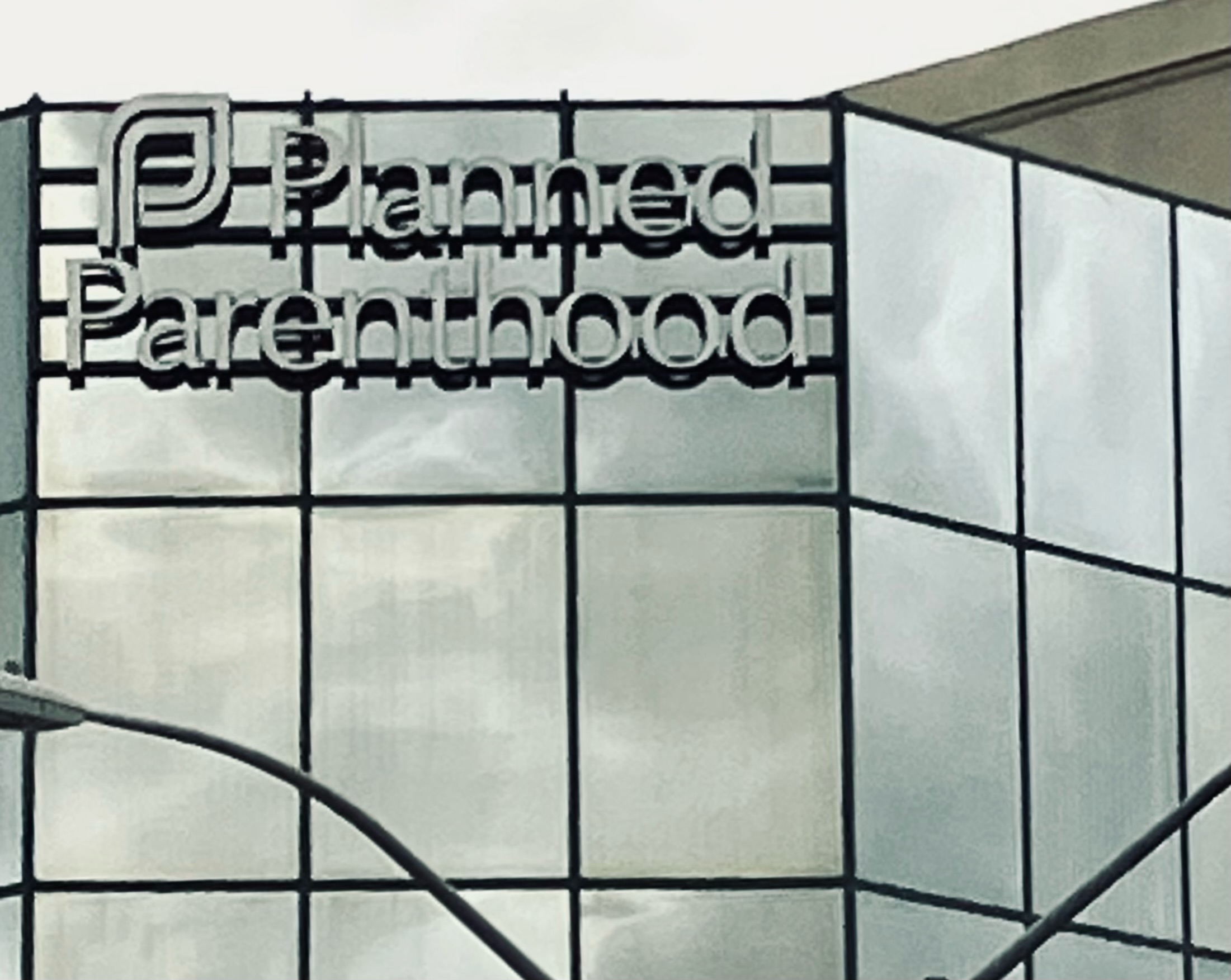 Corner of an all glass building with a Planned Parenthood sign