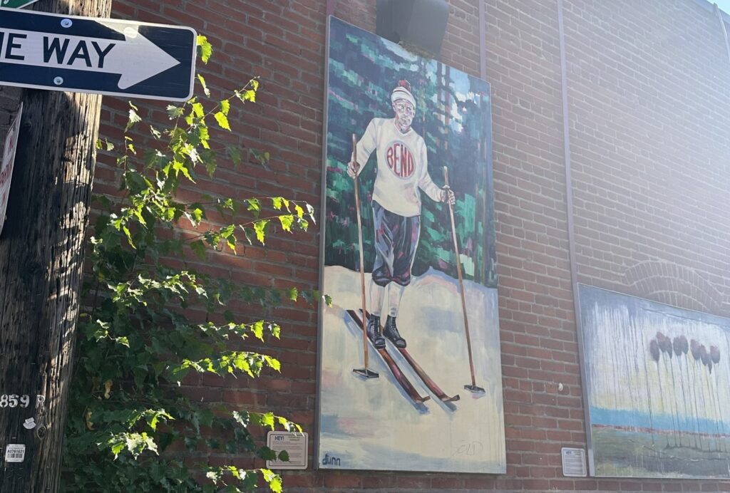 A painted scene of an individual skiing is on top of a brick wall.