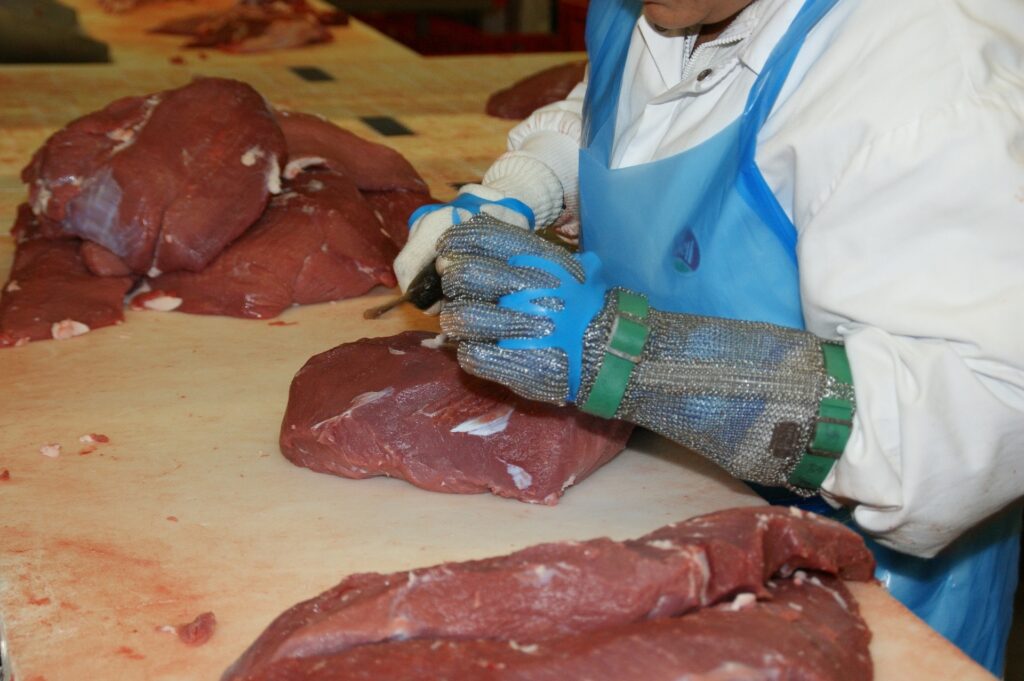 A Person in uniform with protective gearHandles Raw Meat