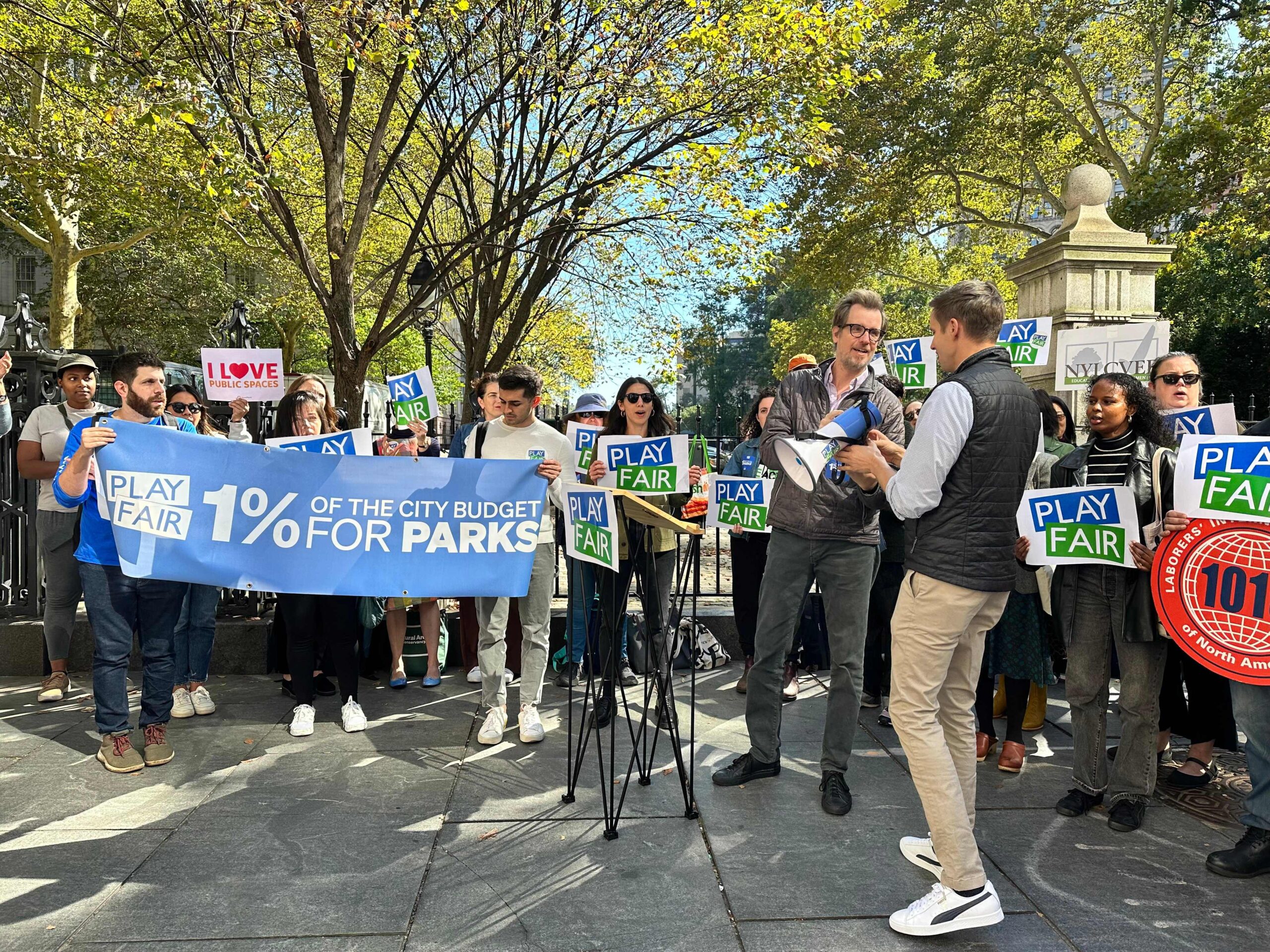 Executive Director of New Yorkers for Parks, Adam Ganser, hands megaphone to council member at a rally in front of City Hall Park.