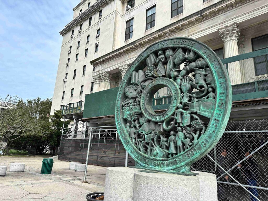 Outside of the Queens County Supreme Court, featuring its emblem (green and rusted).
