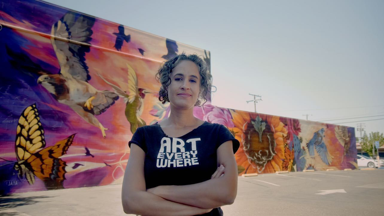 artist jaya king in front of mural