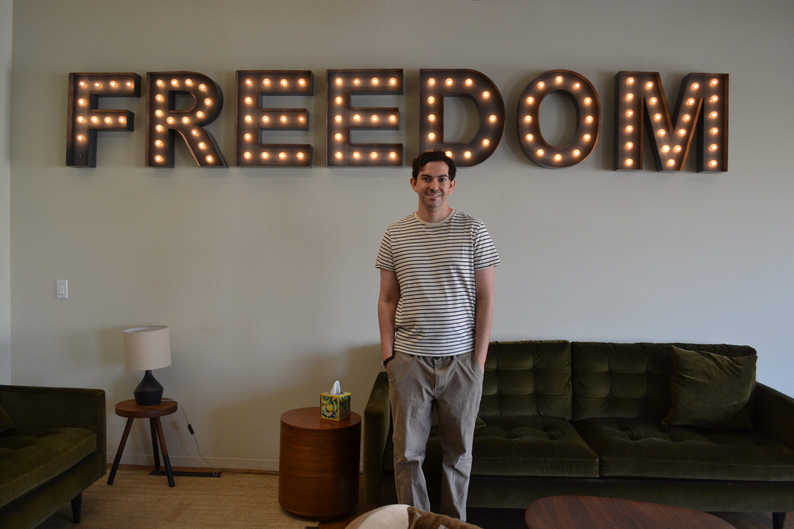 Josh Pynoos of Anti-Recidivism Coalition poses for a photo in front of "FREEDOM" sign.