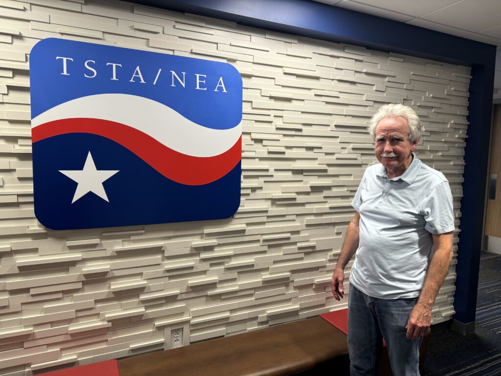 Clay Robison stands in front of the TSTA logo.