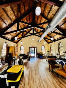 MAP team members organize storage boxes and various items a scattered around a spacious room with lofted ceilings.