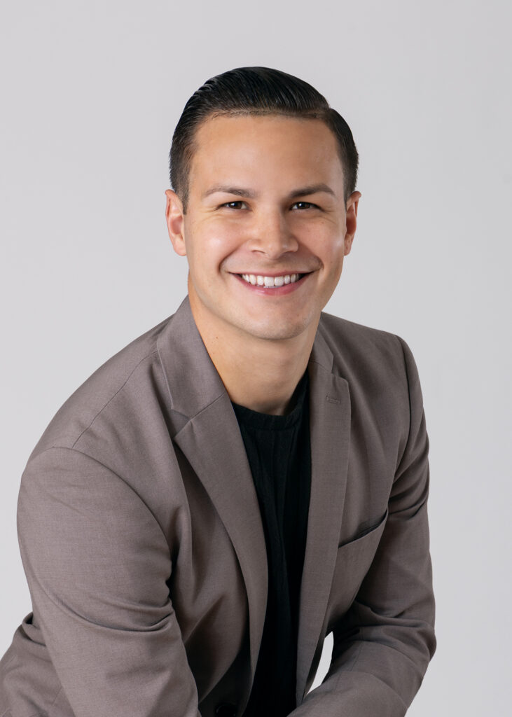 Carlos Foster wearing a gray blazer and black shirt, smiling