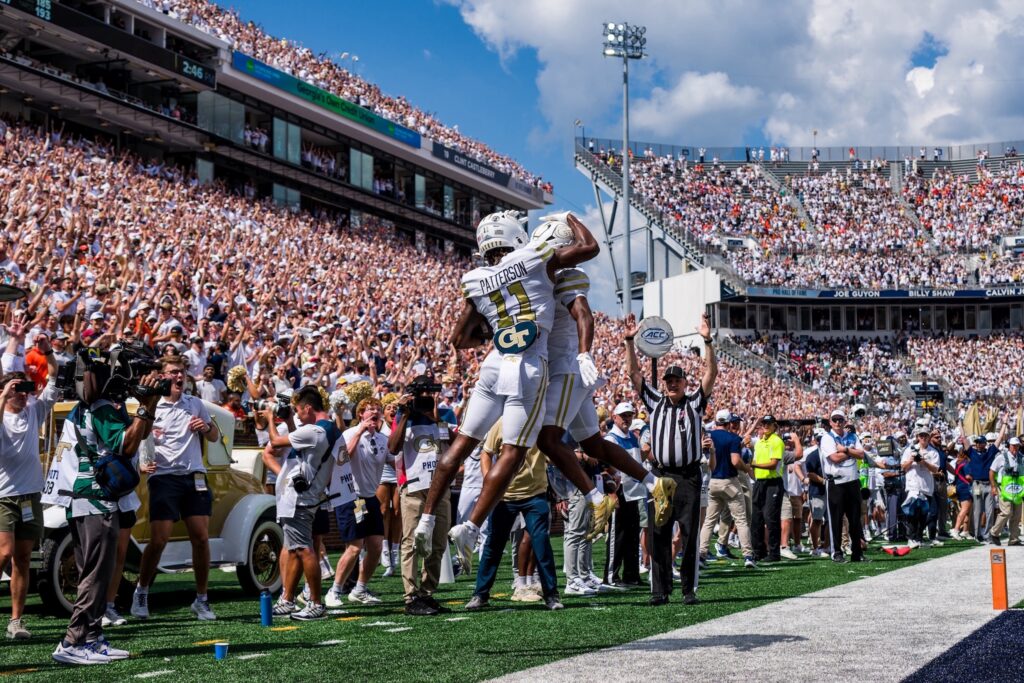 Football player jumping up with a teammate as the referee declares a touchdown in the background