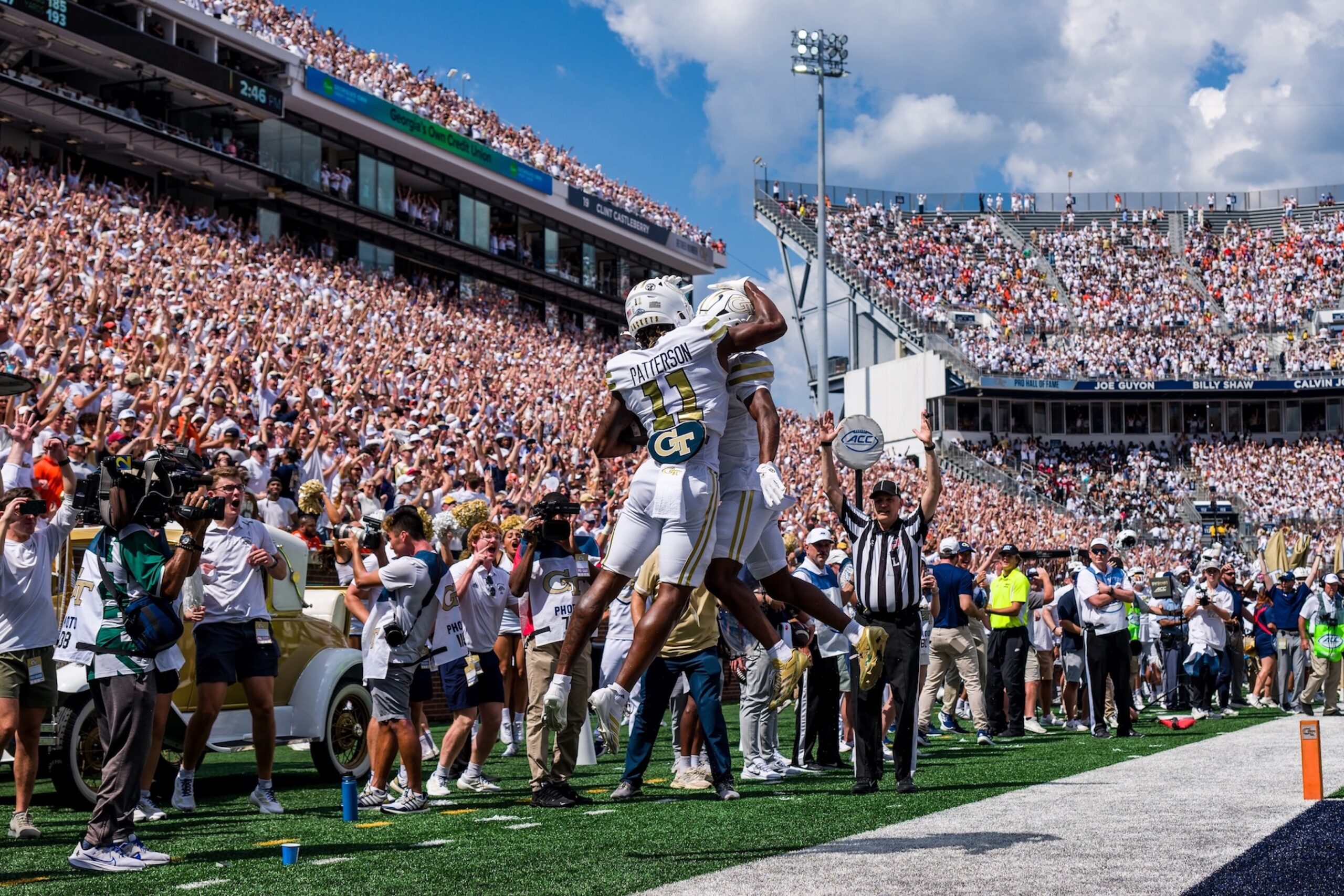 Football player jumping up with a teammate as the referee declares a touchdown in the background
