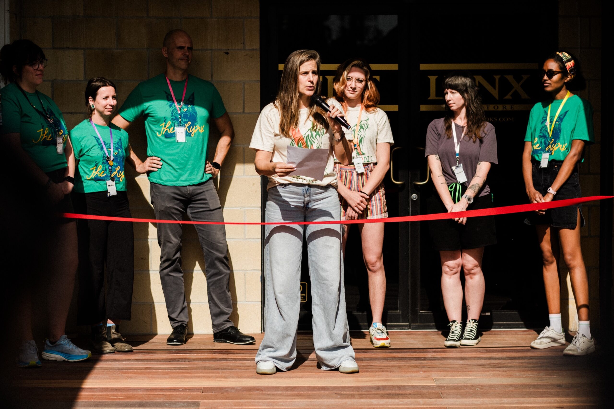 Lauren Groff stands in front of her bookstore with a mic in her hand and a red banner in front of her
