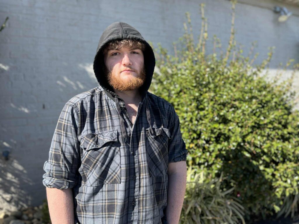 Chase Carswell stands in front a building, wearing a hoody