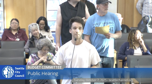 Man speaks into microphone at city council meeting