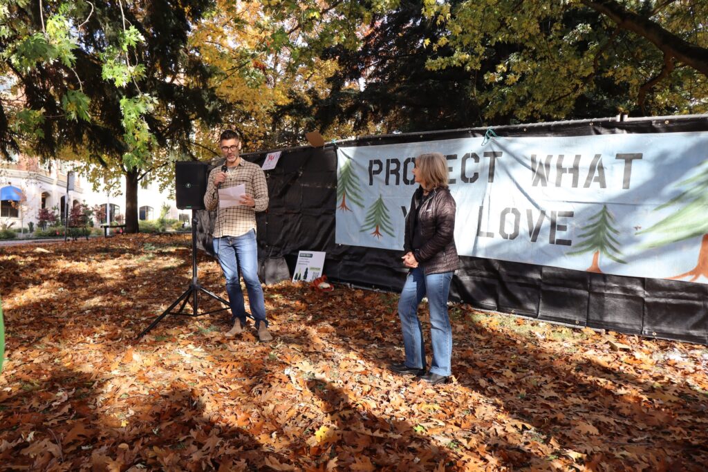 Photo of two individuals in front of tree protection banner