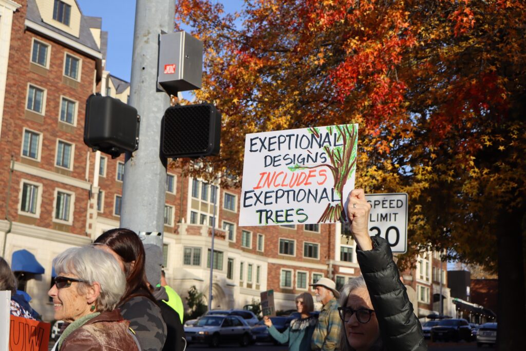 Sign held aloft in front of tree foliage