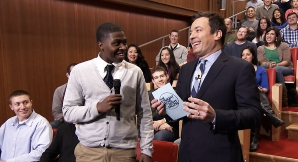Young man and Jimmy Fallon stand in preparation for a bit on Fallon's late night TV show