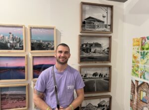 Portrait of photographer Colby Edward Kohn standing in front of his pictures