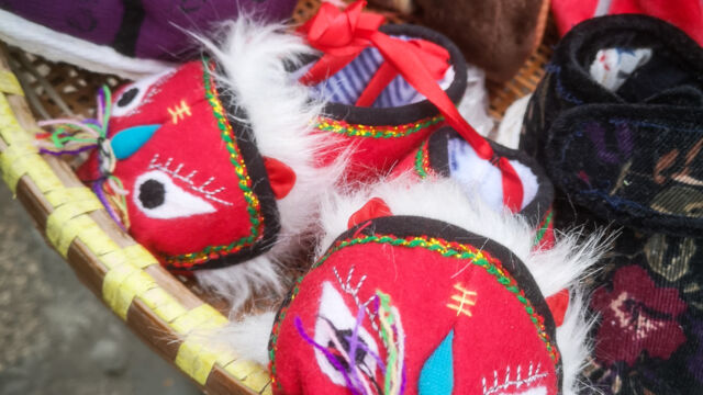 Lion slippers are traditional gifts in China for new babies. This pair was hand sewn by Mrs. Liu, an 86-year-old resident of Qing Guo Alley. Mrs. Liu has been making and selling slippers as a hobby since she retired at age 50. Slippers in a basket
