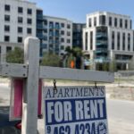 A rental sign outside a Cooper Properties lower rent building looking southwest towards the newer luxury Motif apartment building.