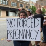 One woman holds a sign saying "no forced pregnancy"