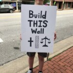 Person holds a sign reading "Build this wall"